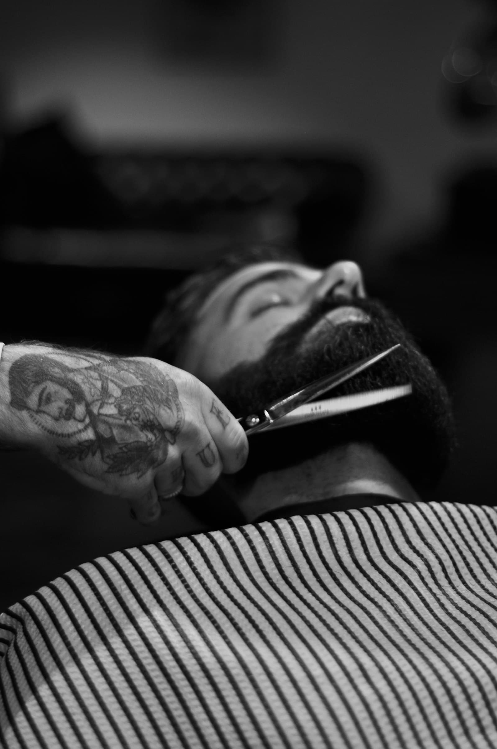 Barber trimming a client's beard with precision shears